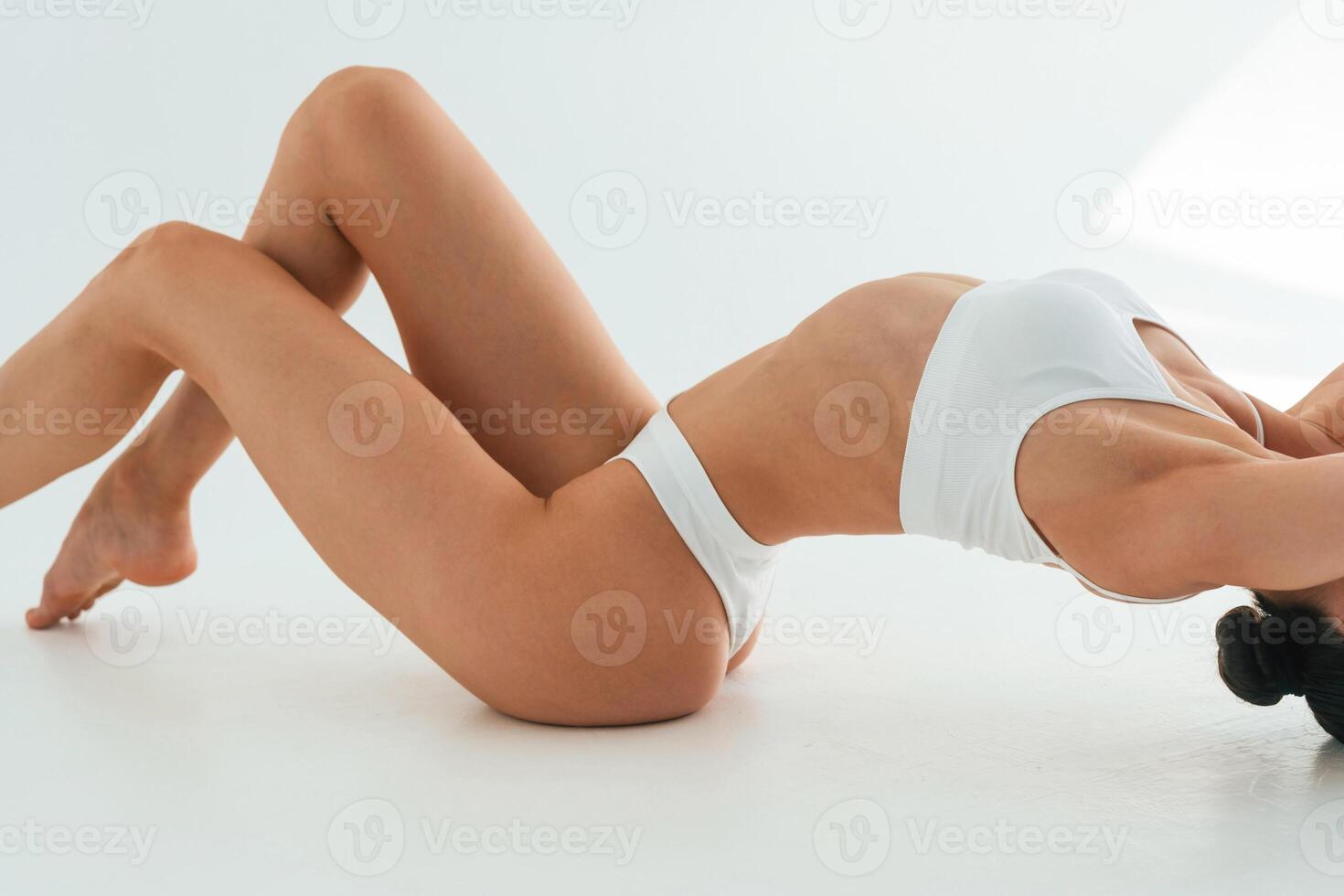 Stretching on the floor, close up view,. Young woman with slim body type is in fitness clothes in the studio photo