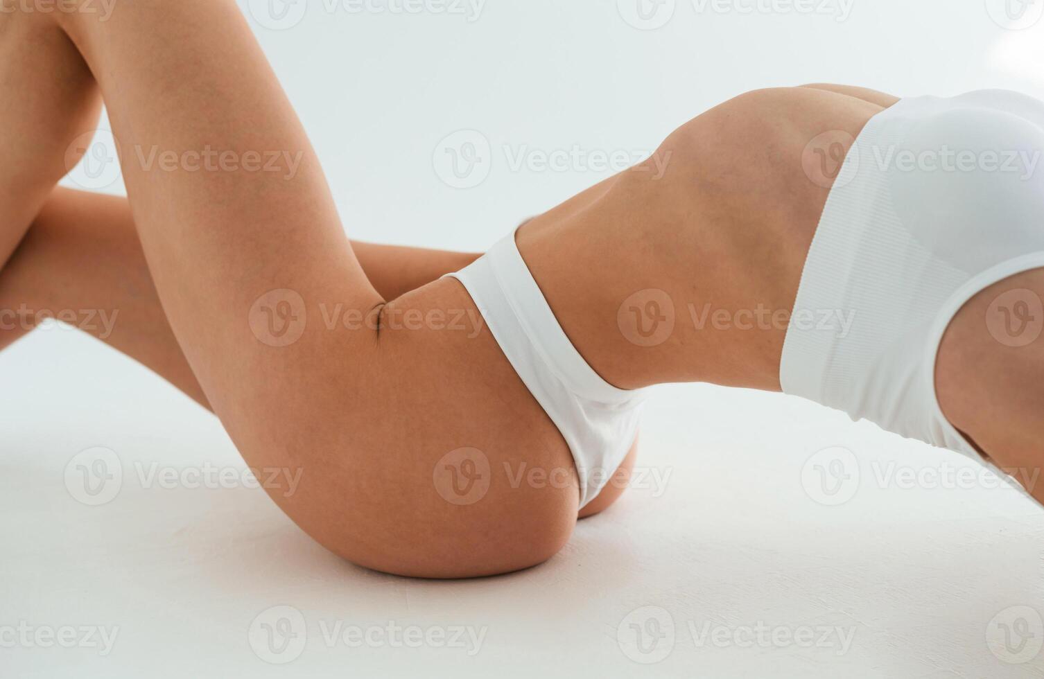 Close ,up view of belly, on the floor. Young woman with slim body type is in fitness clothes in the studio photo