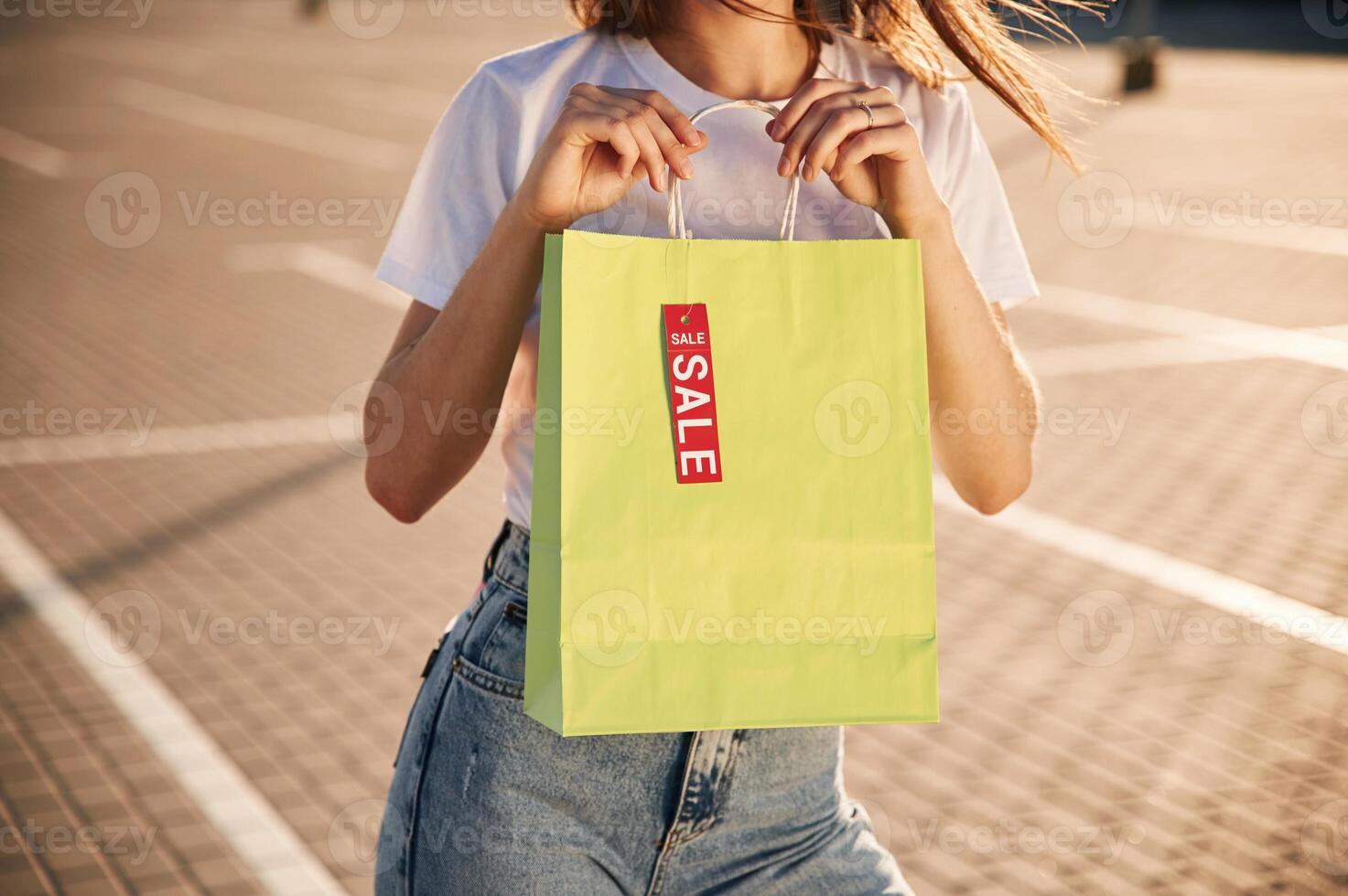 Sale ,sticker. Beautiful, woman, in casual clothes is holding shopping bags, outdoors photo