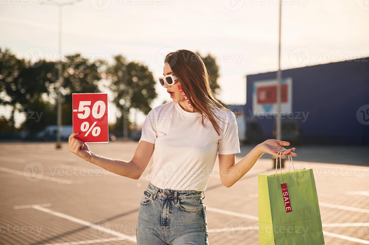 Big sale.. Beautiful woman in casual, clothes is holding shopping bags, outdoors photo