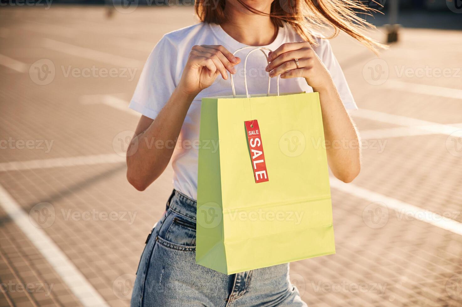 Sale sticker. .Beautiful woman ,in casual clothes is holding shopping bags, outdoors photo