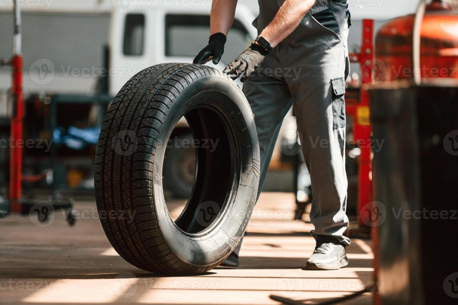 Rolling the wheel. Man is works in ,the ,automobile repairing salon photo