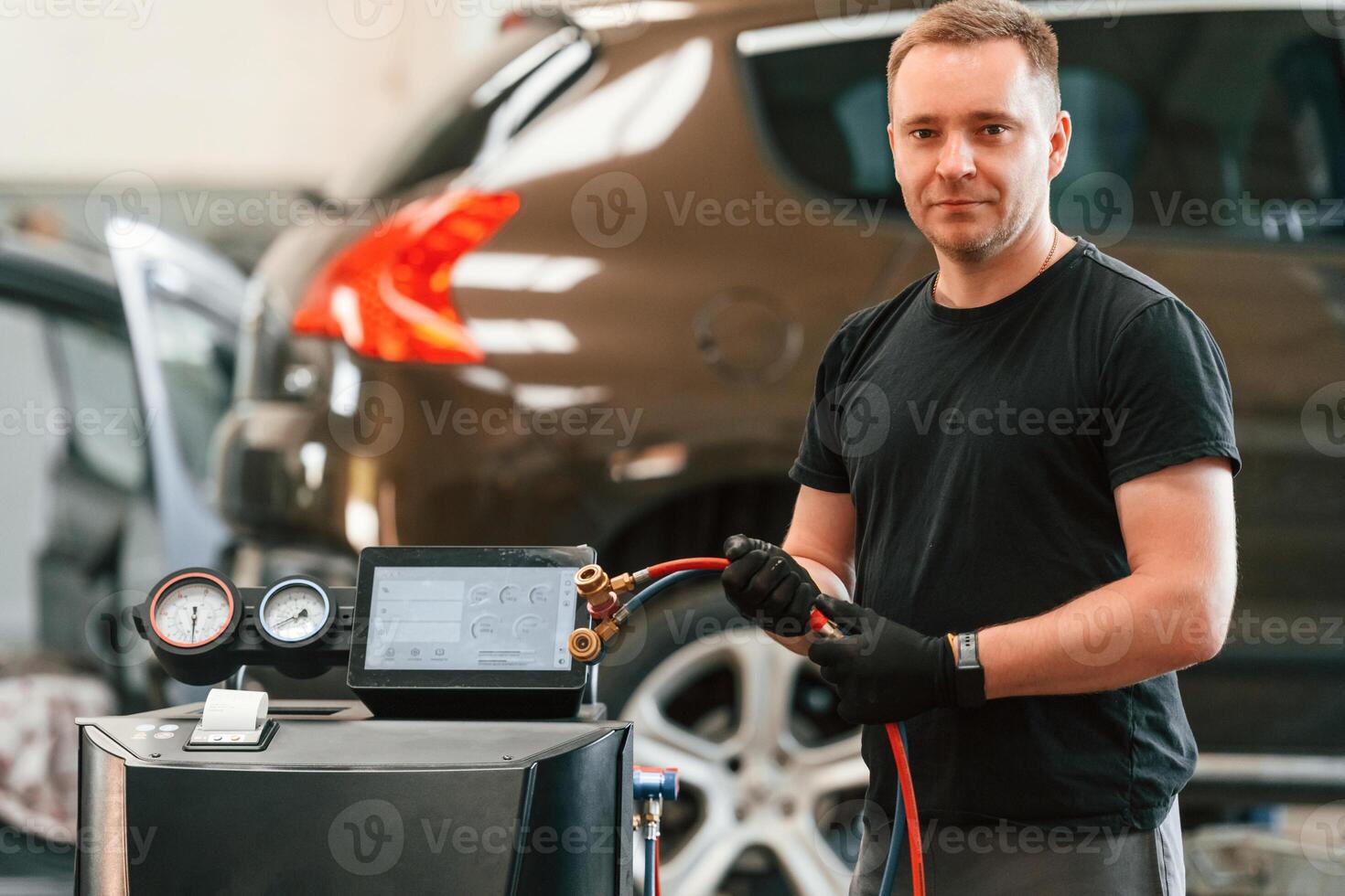 With wires in hands. Man is works in the automobile repairing salon photo