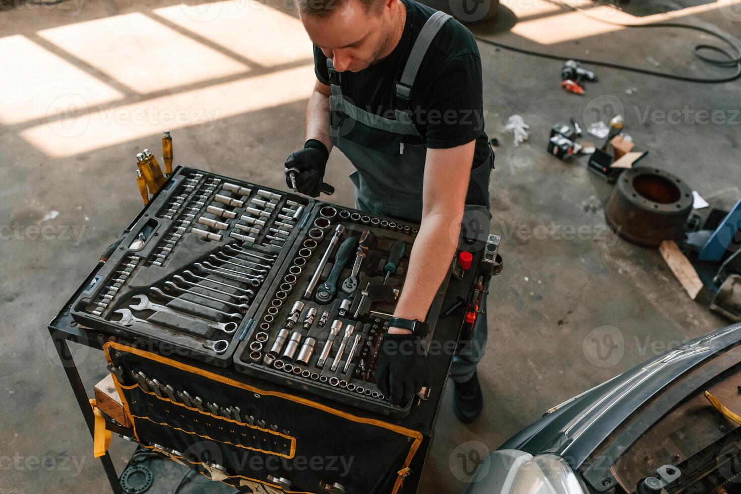 Top view of employee that standing, by the toolbox. Man is works in the automobile repairing salon photo