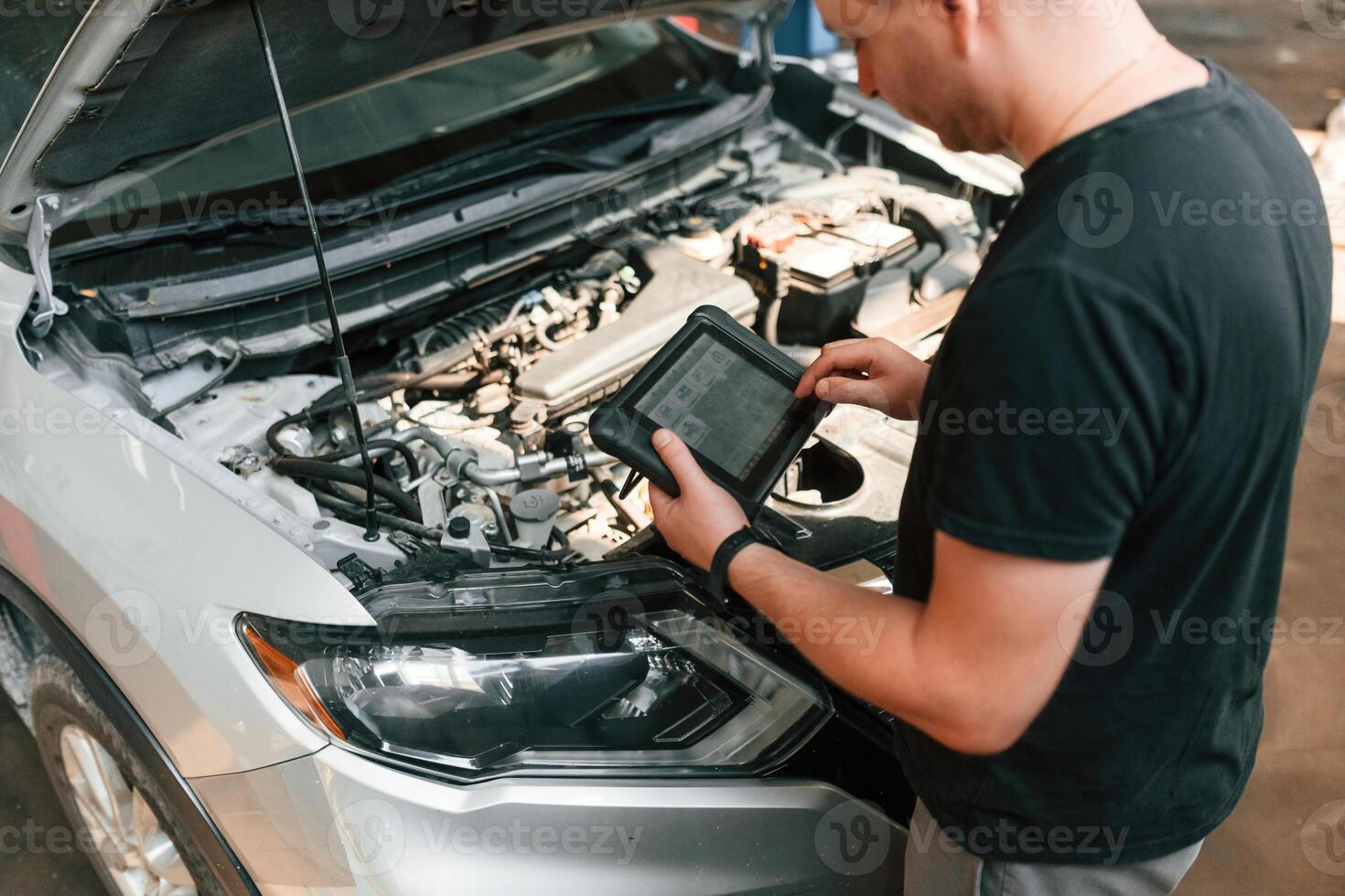 Holding the ,tablet. Man is works in the automobile repairing salon photo