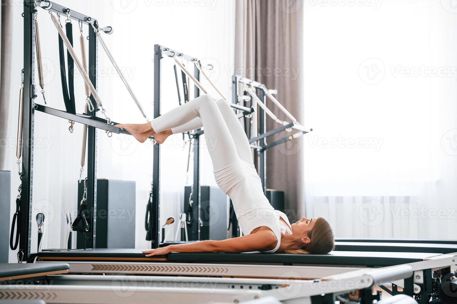 Lying down and stretching legs,. Young woman in fitness center is doing exercises photo