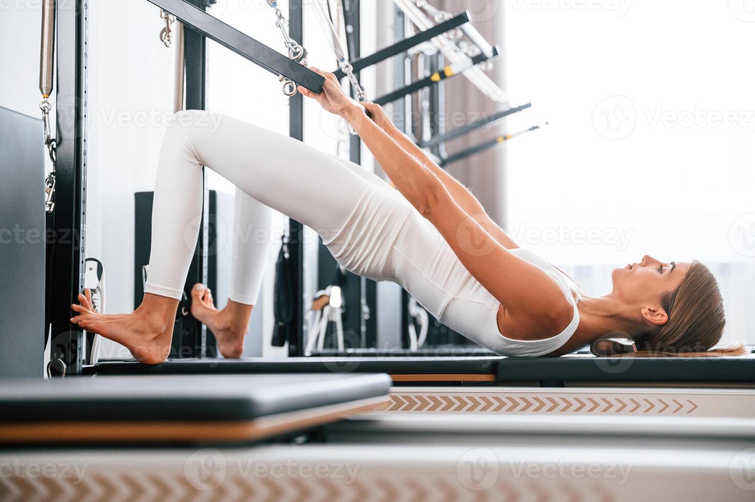 In white ,sportive clothes. Young woman in fitness center is doing exercises photo