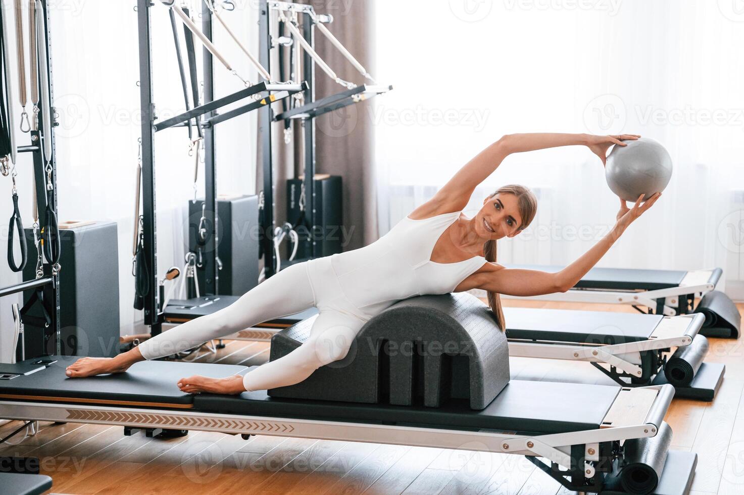 Holding ball in hands. .Young woman in fitness center is doing exercises photo