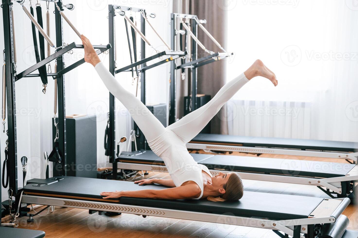 Lying down ,and stretching legs. Young woman in fitness center is doing exercises photo