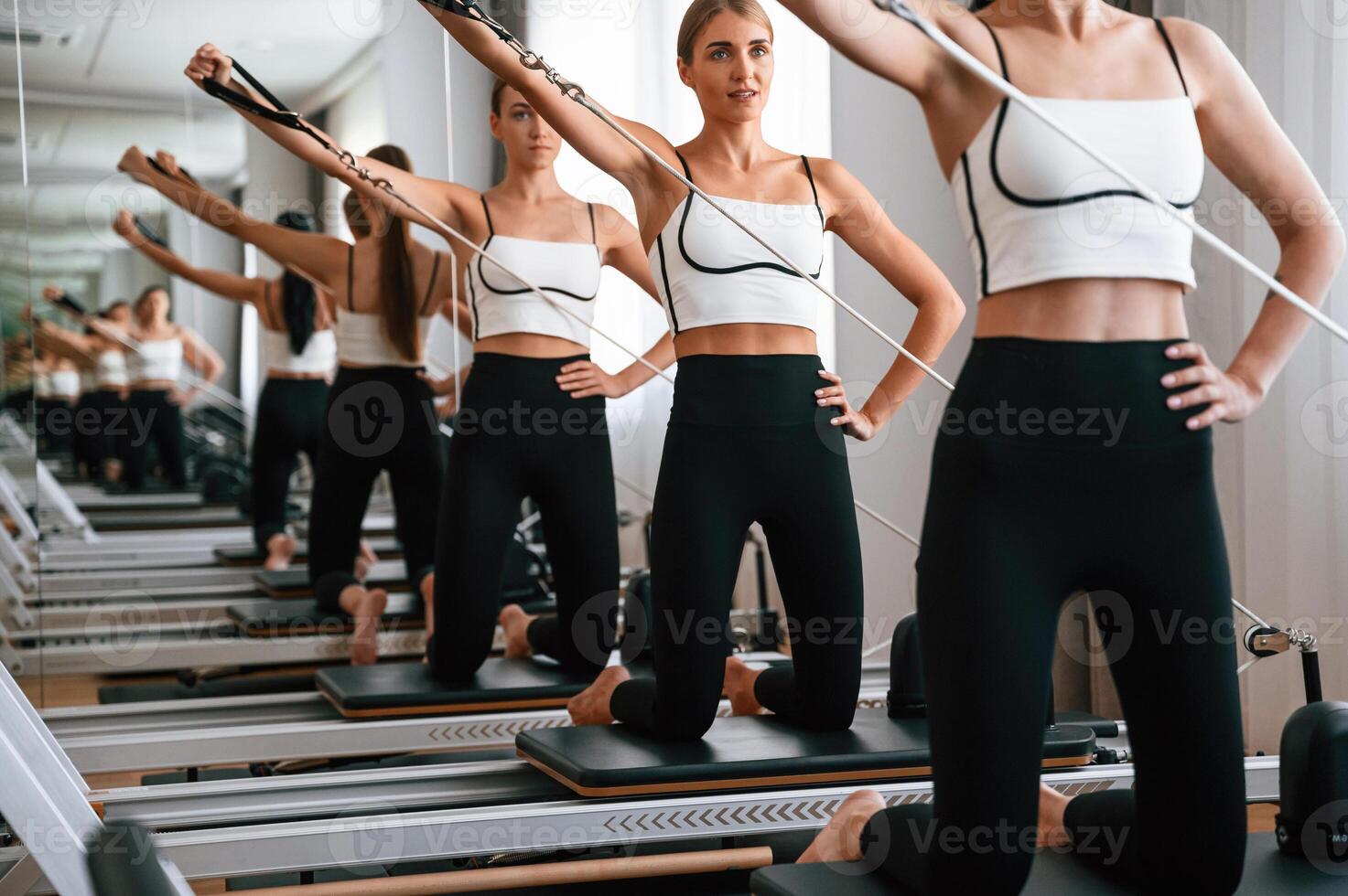 Against the mirror. Women ,in fitness center are doing exercises photo