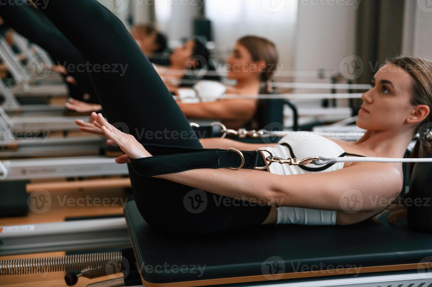 Lying ,down in a row and doing stretches. Women in fitness center are doing exercises photo