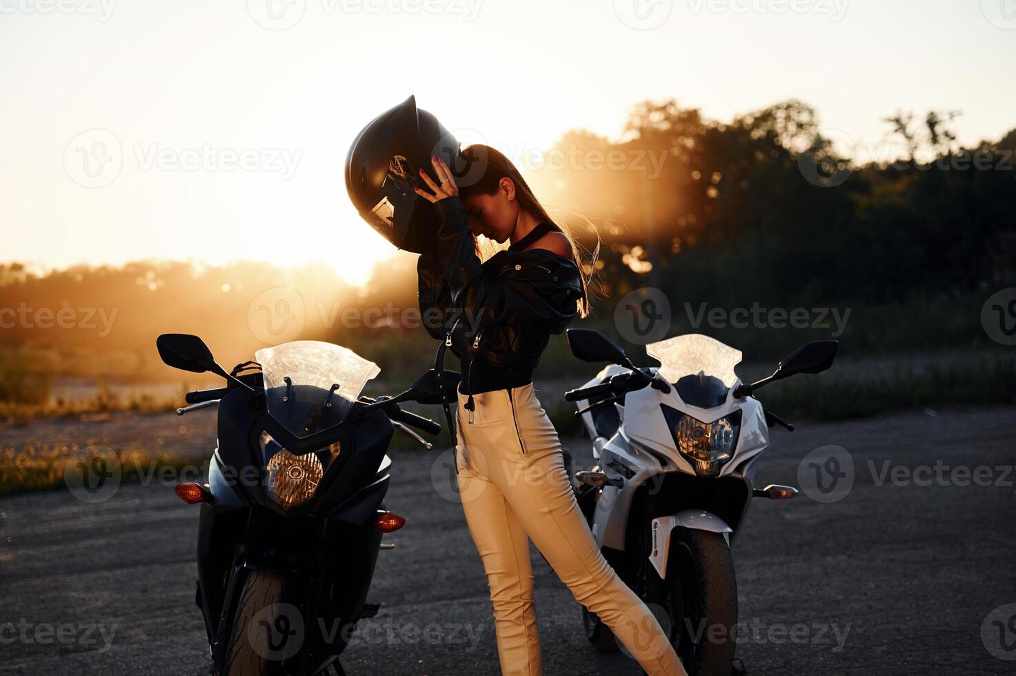 Against beautiful sunlight. Woman is with motorcycle outdoors photo