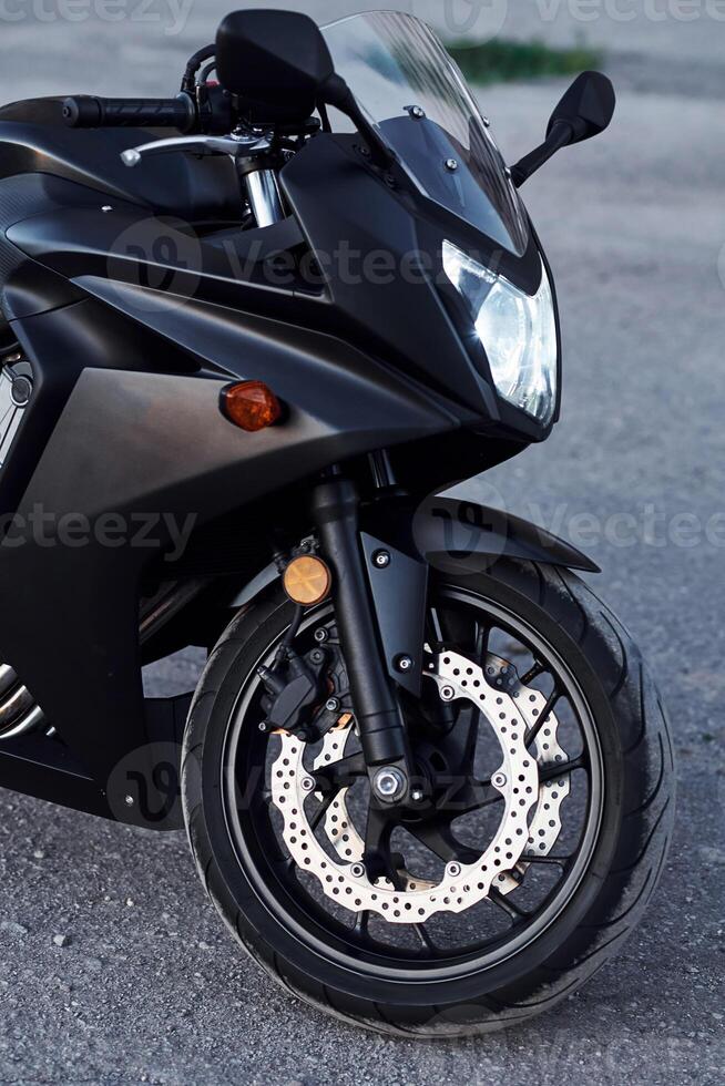 Black colored, vehicle. Close up view of modern motorcycle that is parked outdoors photo