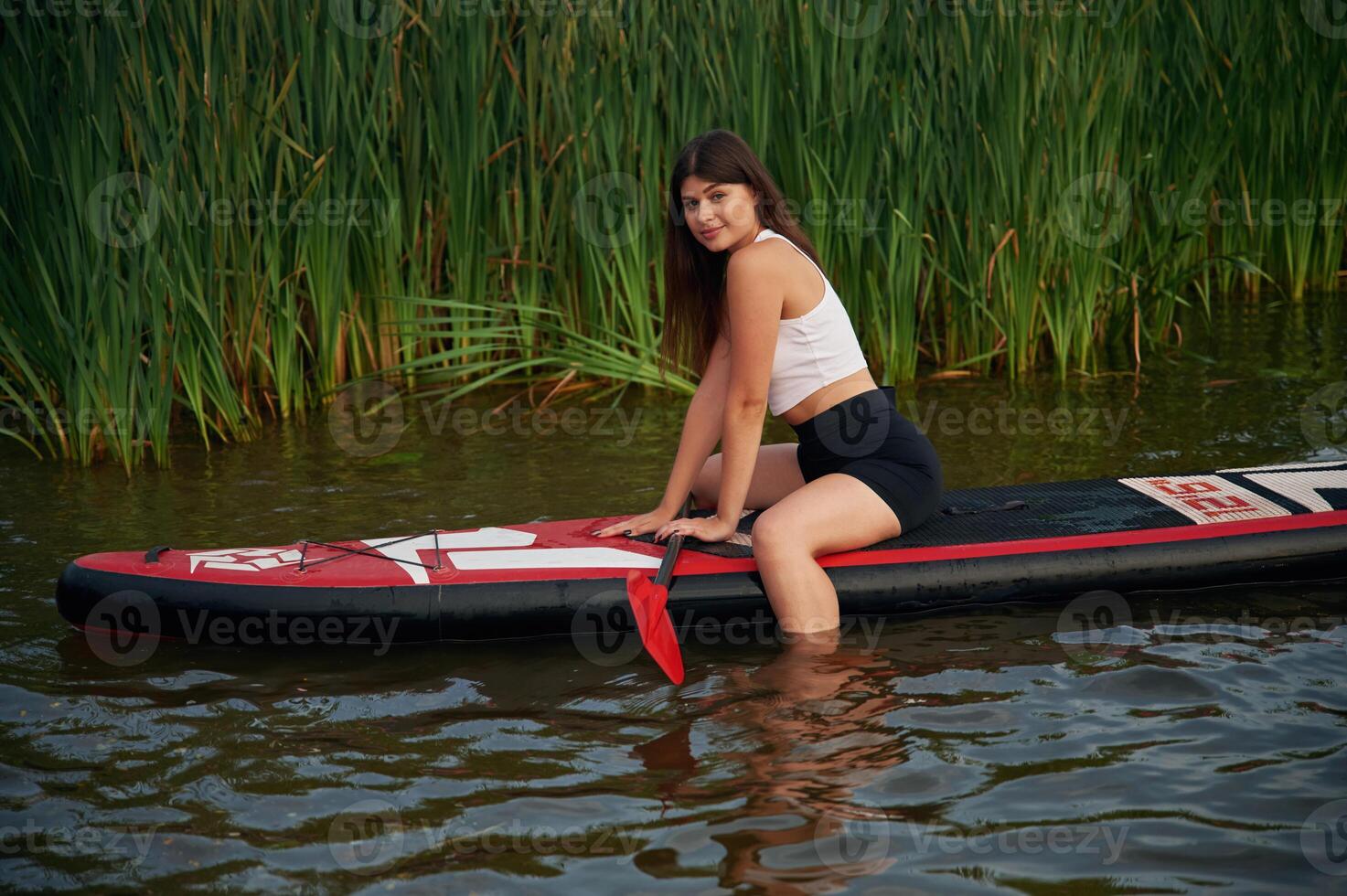 Sitting, relaxing, enjoying the ,nature. Young woman is on sup boards in the lake photo