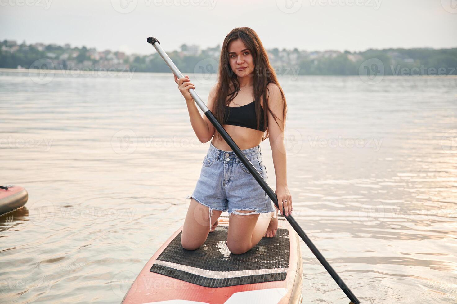 On the knees.. Young woman is on sup boards in the lake photo