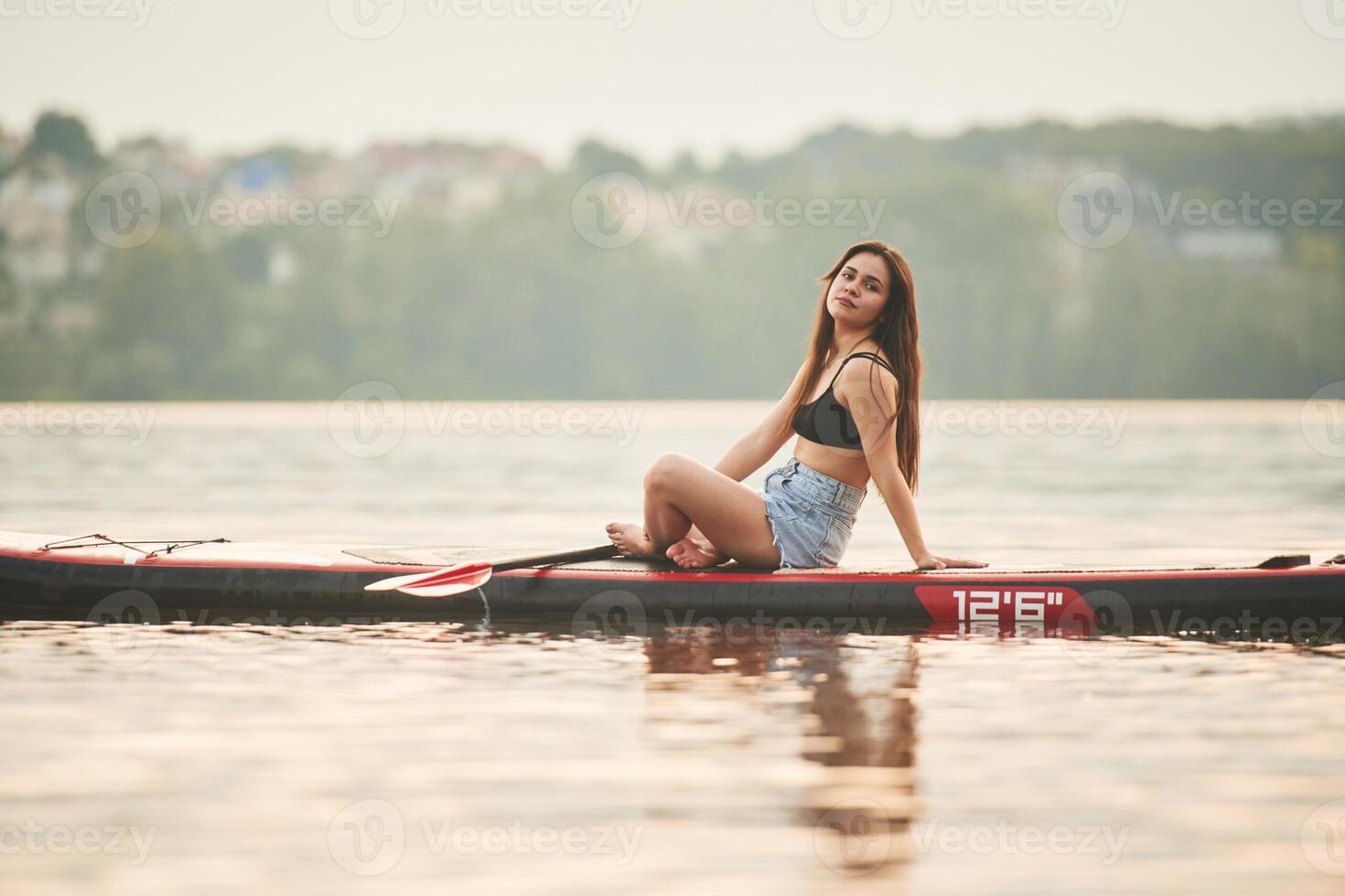Forest ,and, houses on background. Young woman is on sup boards in the lake photo