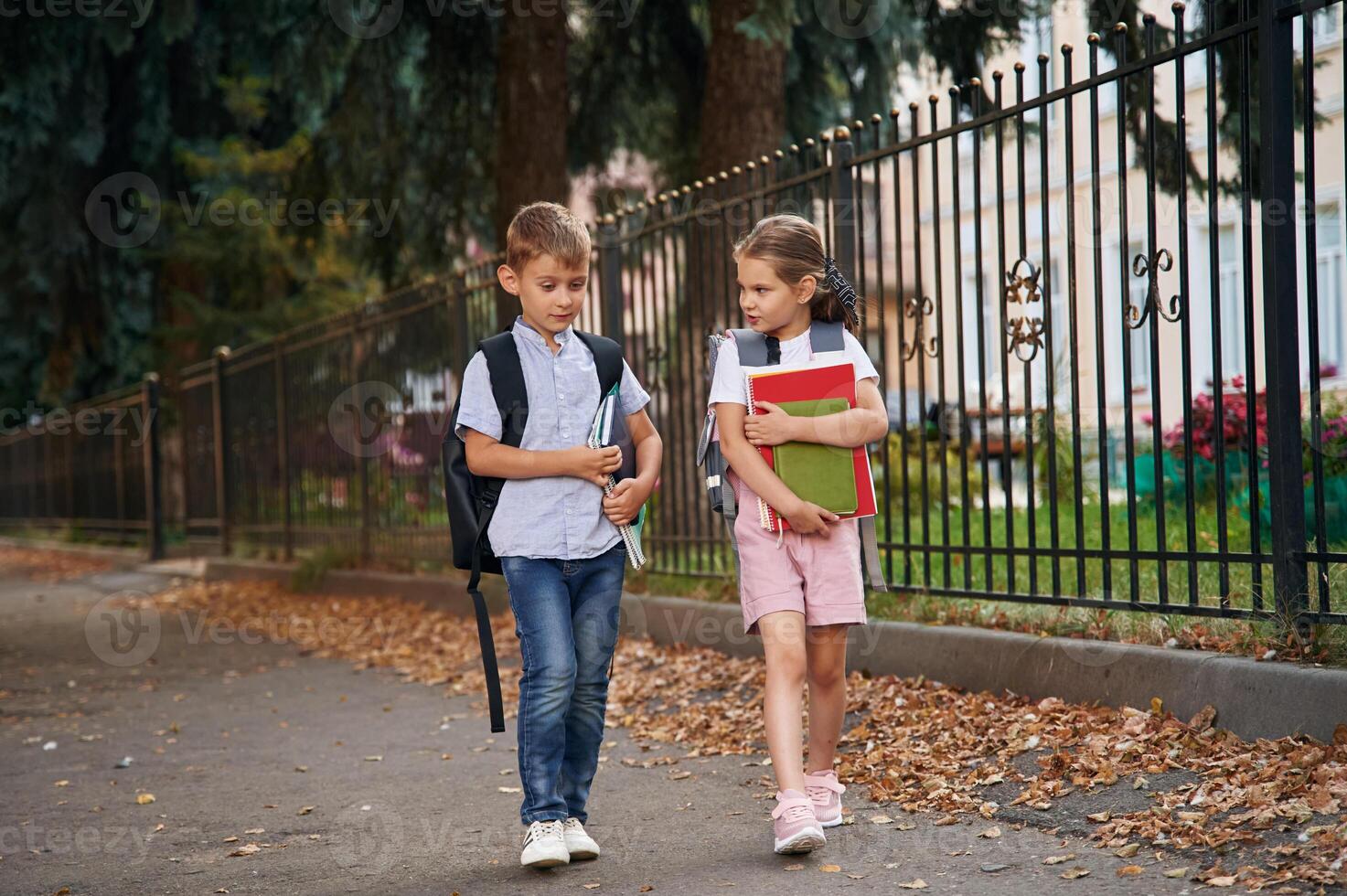 Holding ,notebook and books.. Young ,school children of boy and girl are together outdoors photo