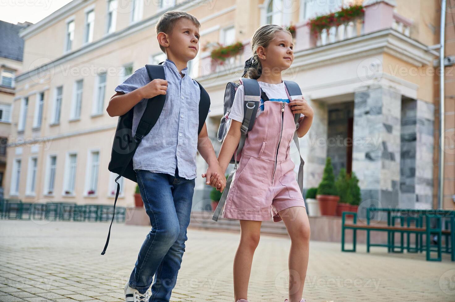 Holding hands, walking. Young school children of boy and girl are together outdoors photo