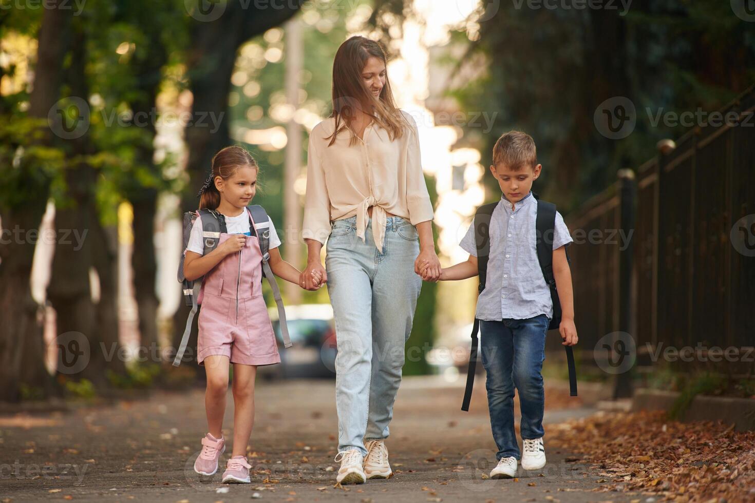 Holding hands, walking together. Woman with two kids are going to school, conception of education photo