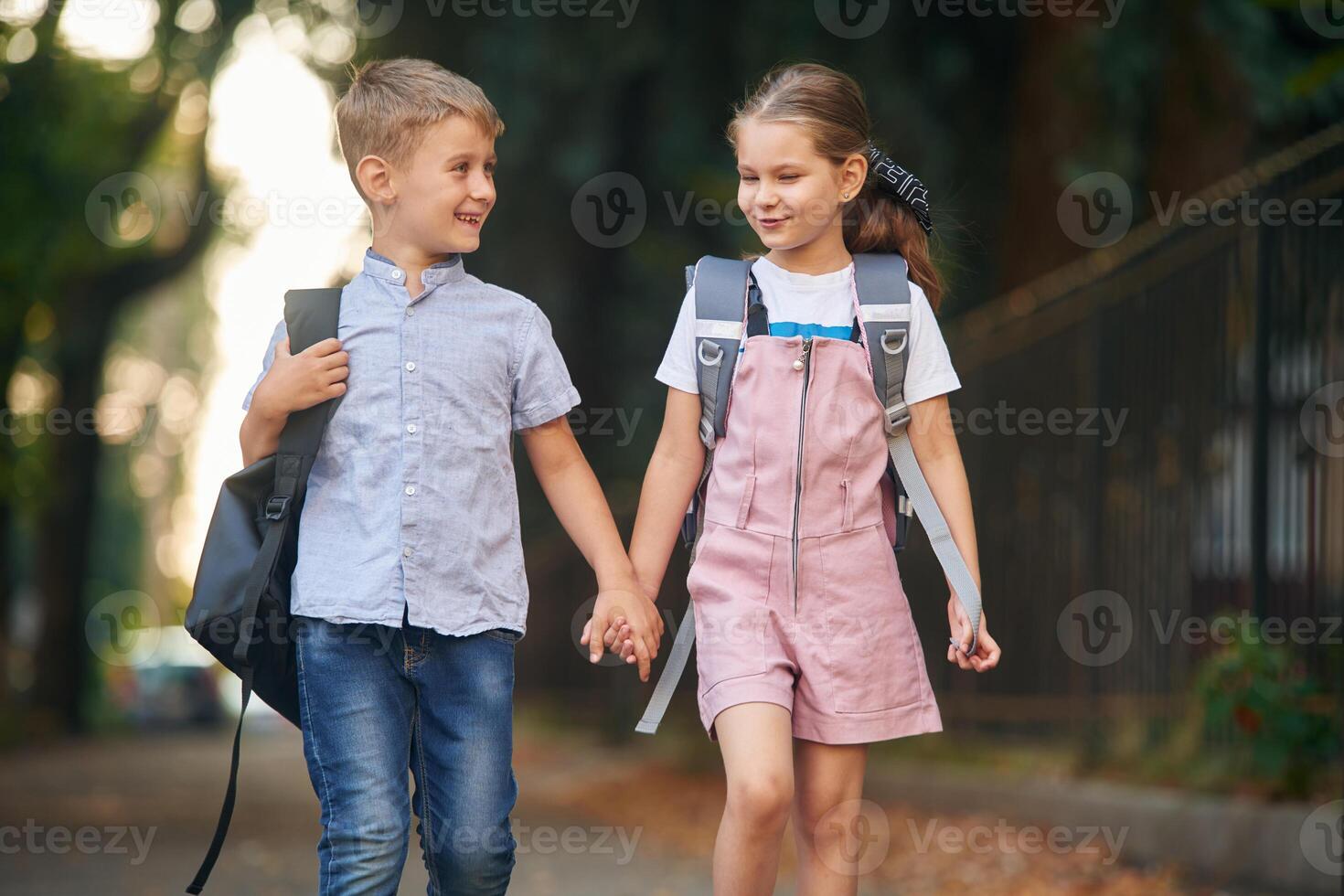 Front view, walking, together.. Young school children of boy and girl are outdoors photo