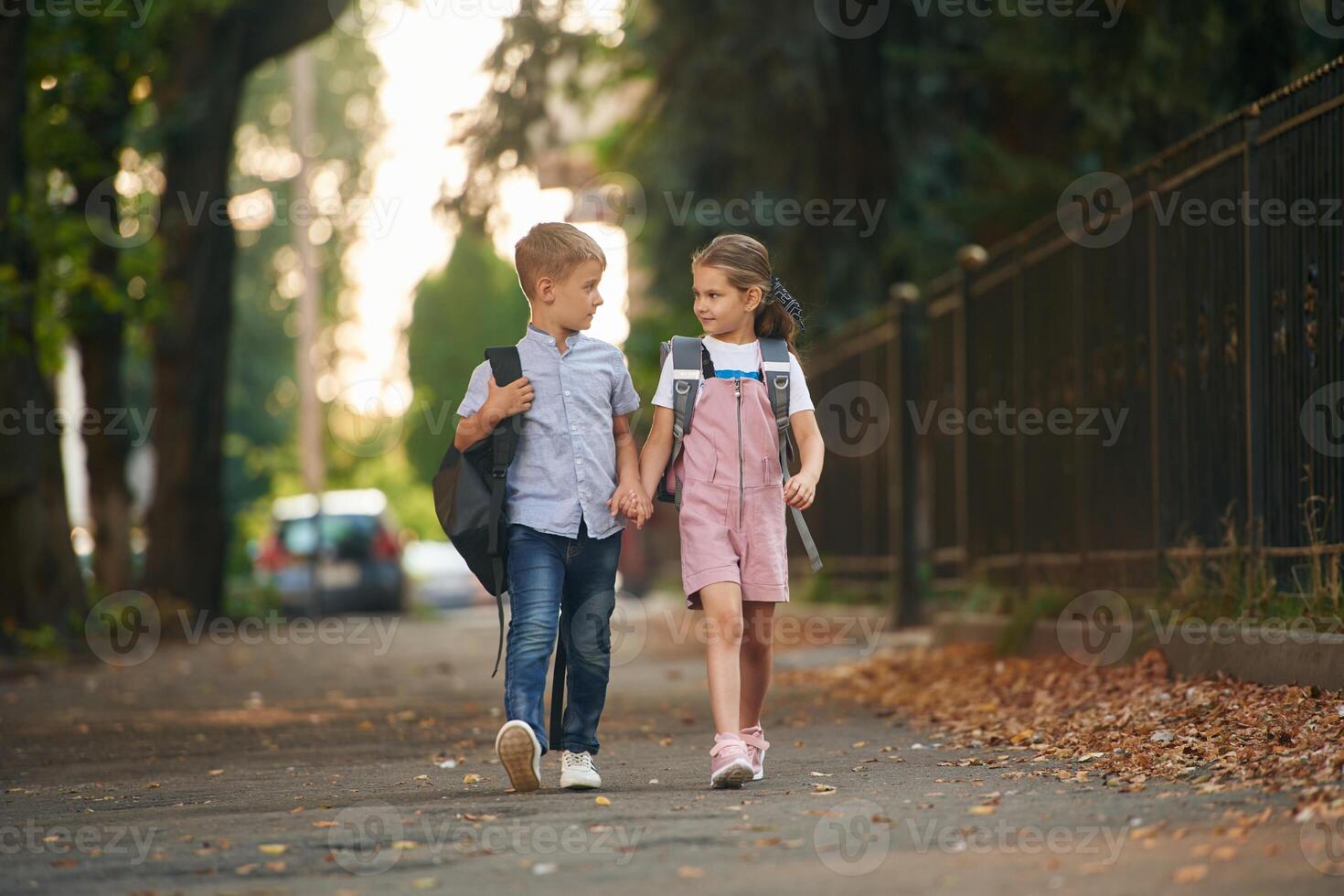 Front view, walking, together. Young school children of boy and girl are outdoors photo