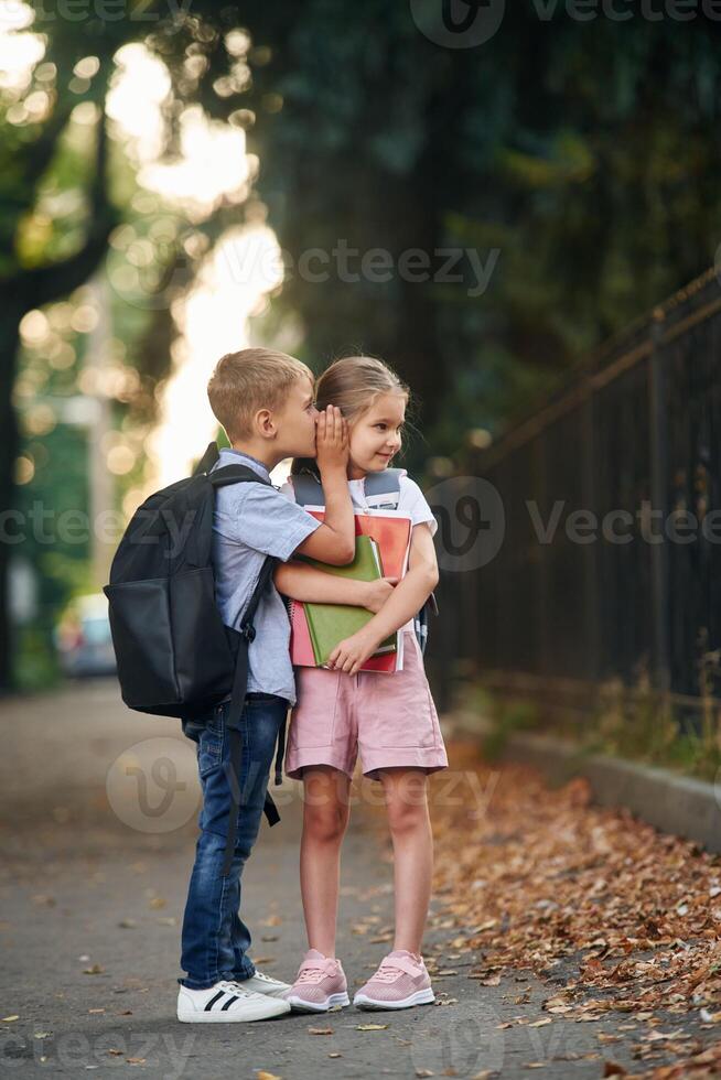 To gossip. Young, school children of boy and girl are together outdoors photo