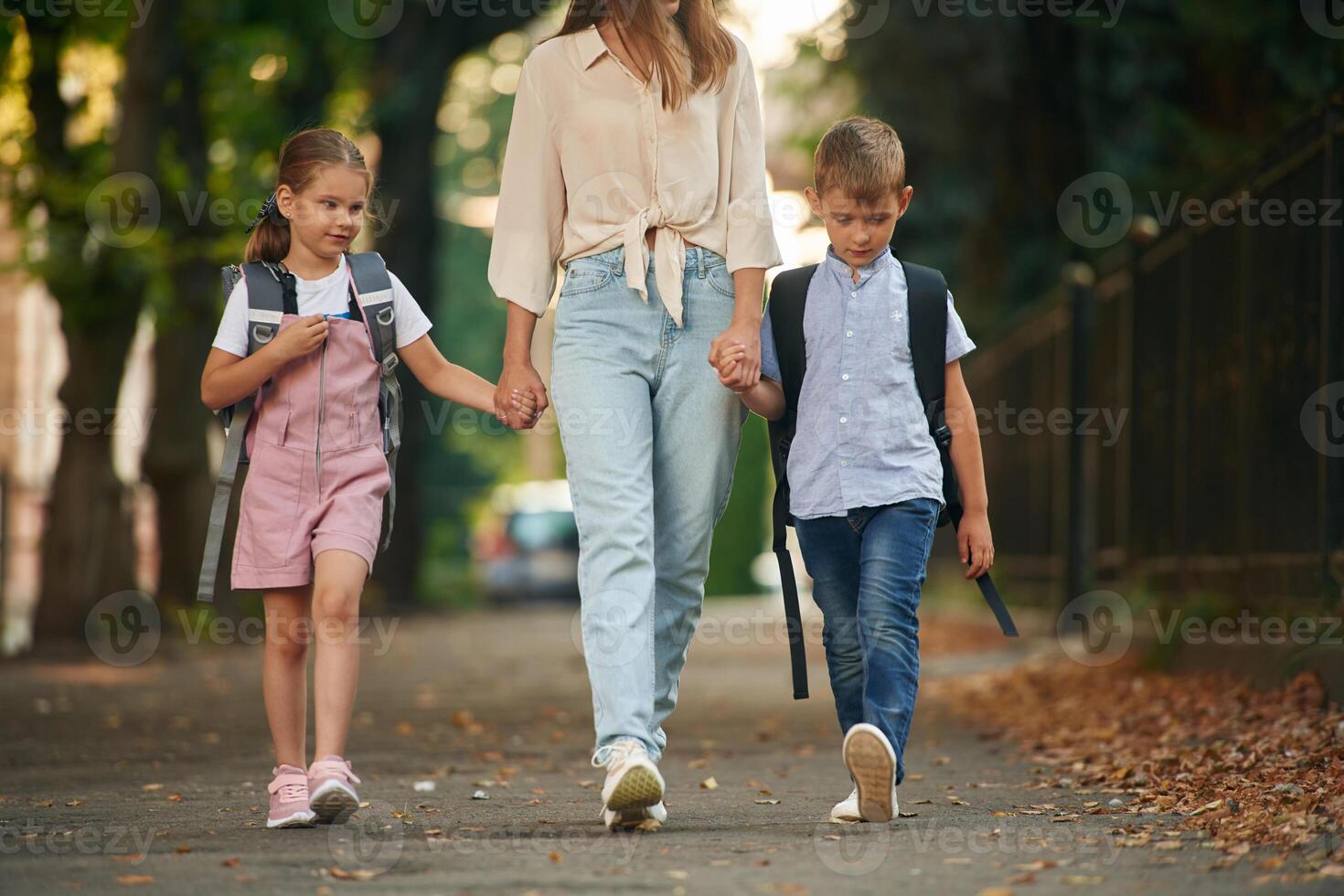 Holding ,hands,, walking together. Woman with two kids are going to school, conception of education photo