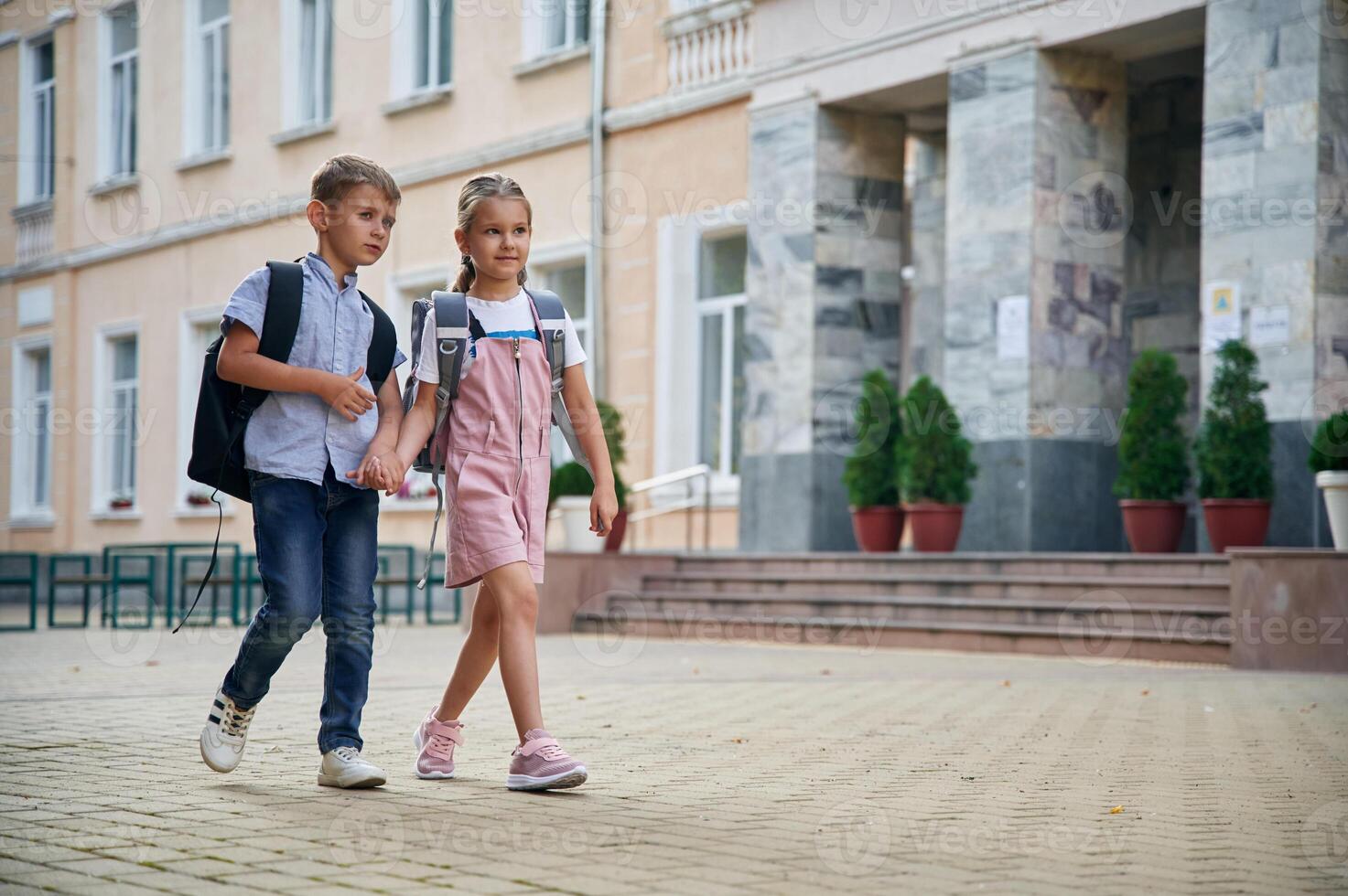Holding ,hands, walking. Young school children of boy and girl are together outdoors photo