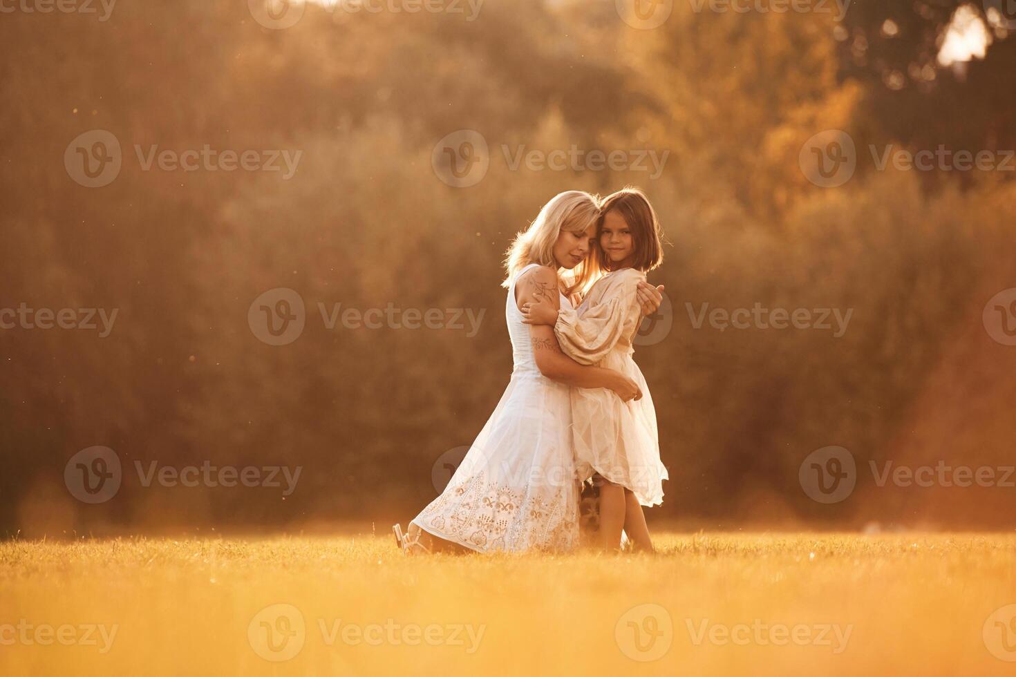 Embracing ,each other. Woman with her daughter is on the summer field photo