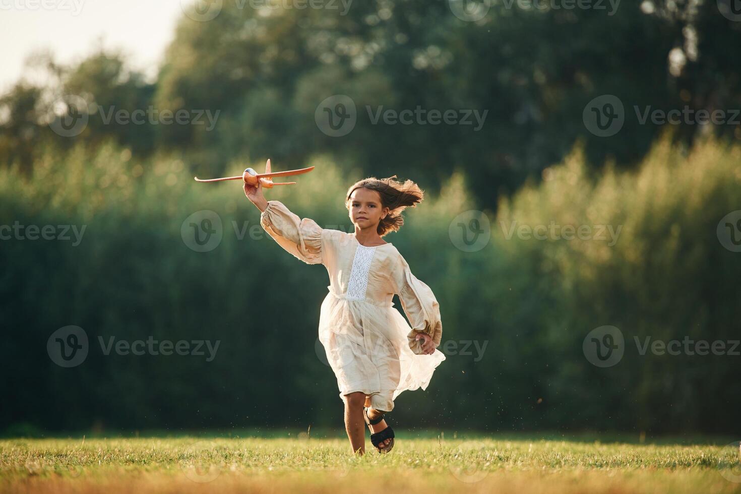 Running, with, toy plane. Little girl is on the summer field outdoors photo