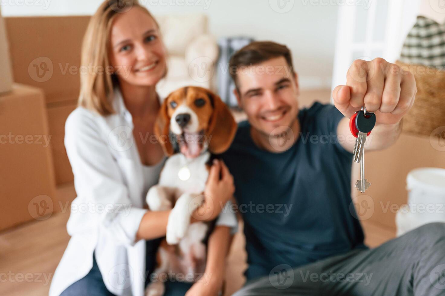 Holding, keys, for new appartment. Young couple with dog are moving to new home photo