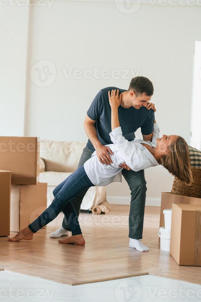 Dancing, celebrating. Young couple moving to new home photo