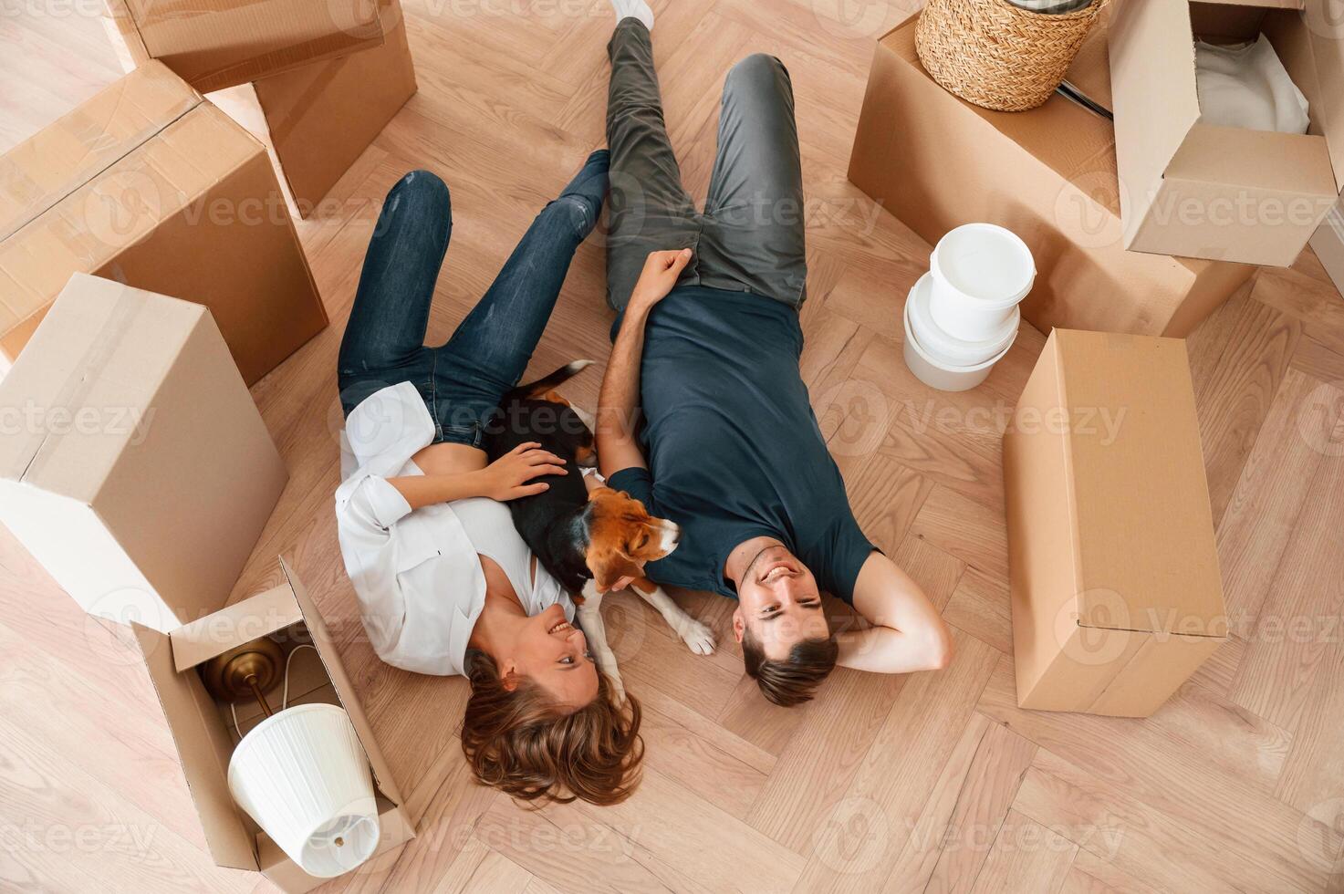 View from the top, lying down ,and ,resting. Young couple with dog are moving to new home photo