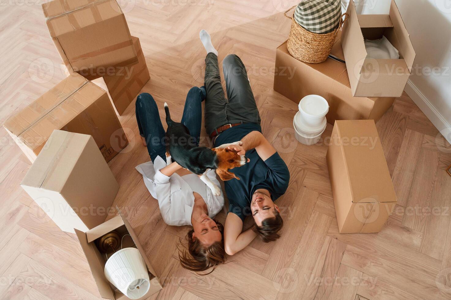 On, the, floor, lying down, top view. Young couple with dog are moving to new home photo
