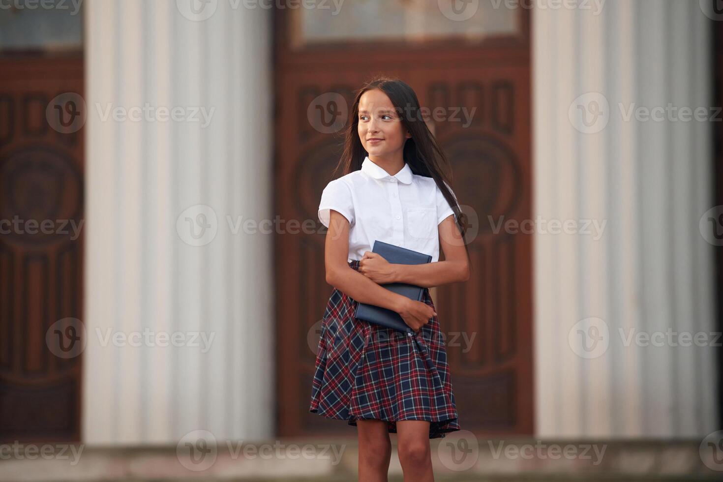 Conception of knowledge.,. School girl in uniform is outdoors near the building photo