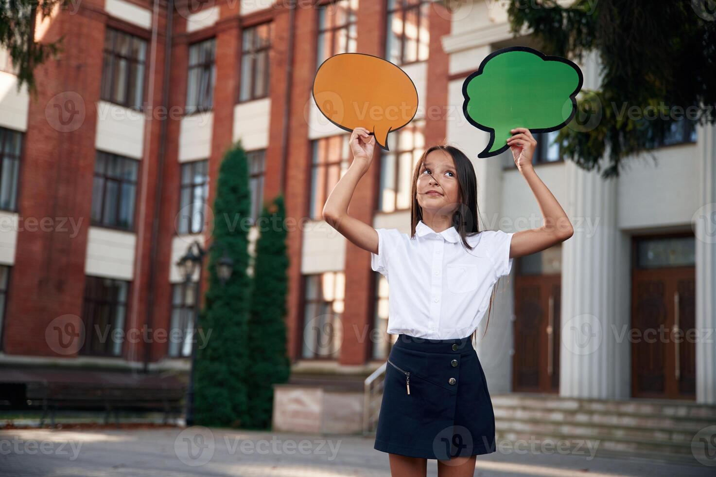 Colorful stickers in hands,, copy space for text, thoughts. School girl in uniform is outdoors near the building photo