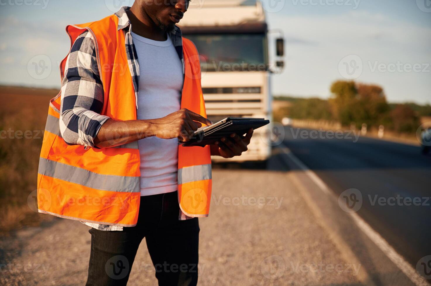 Modern technology concept. With tablet. Black man is standing on the road with truck on it photo