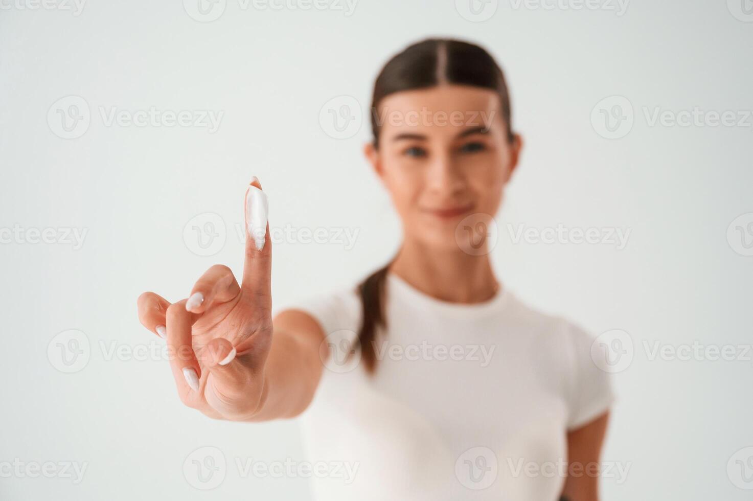 Young ,woman, is standing with cream for the face. In the studio photo