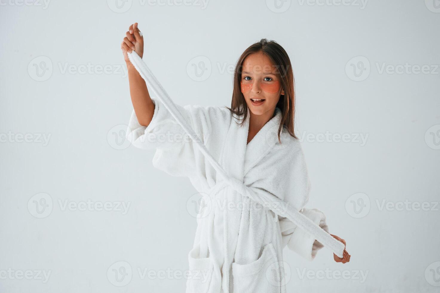 In white robe. Conception of beauty and self care. Young girl is in the studio photo