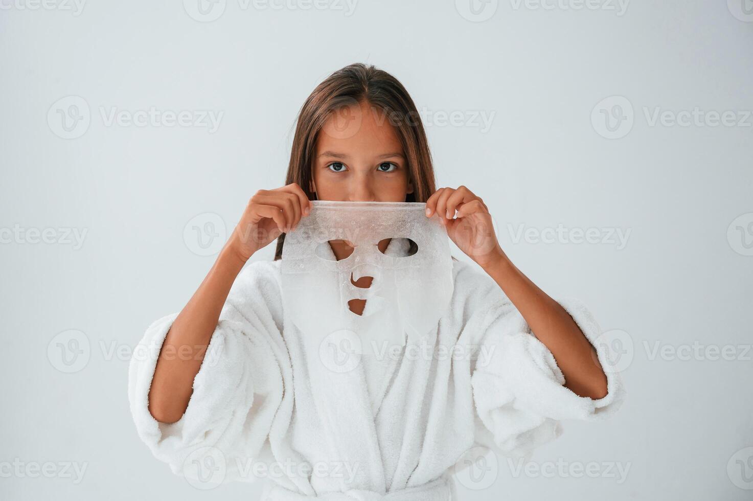 Wearing, off mask for the face. Conception of beauty and self care. Young girl is in the studio photo