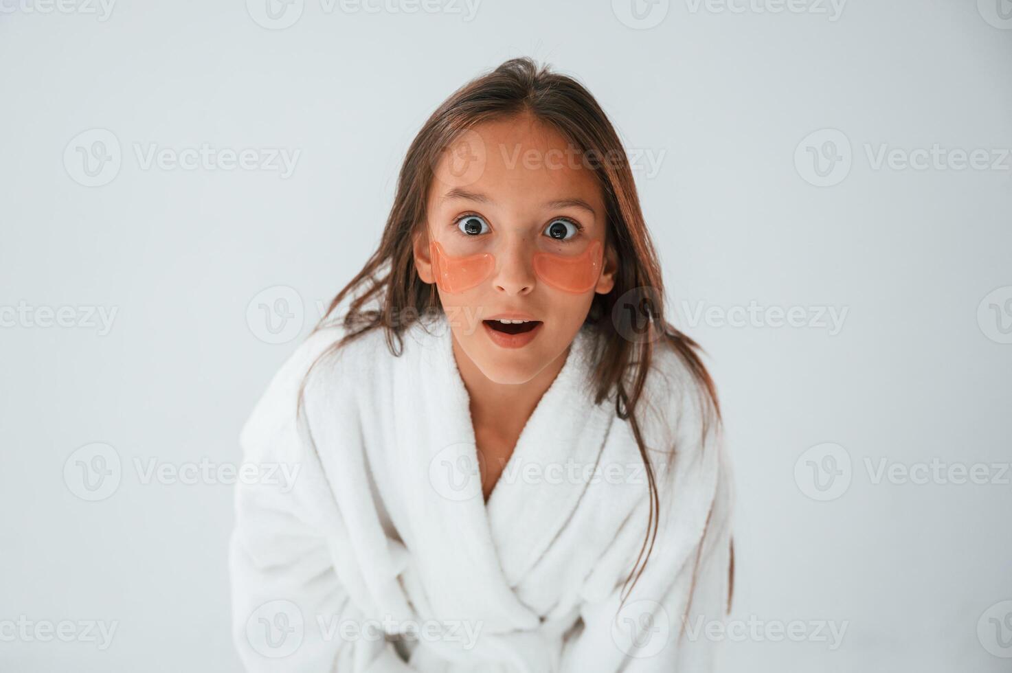 Positive and surprised, facial expression. With eye patches. Conception of beauty. Young girl is in the studio photo