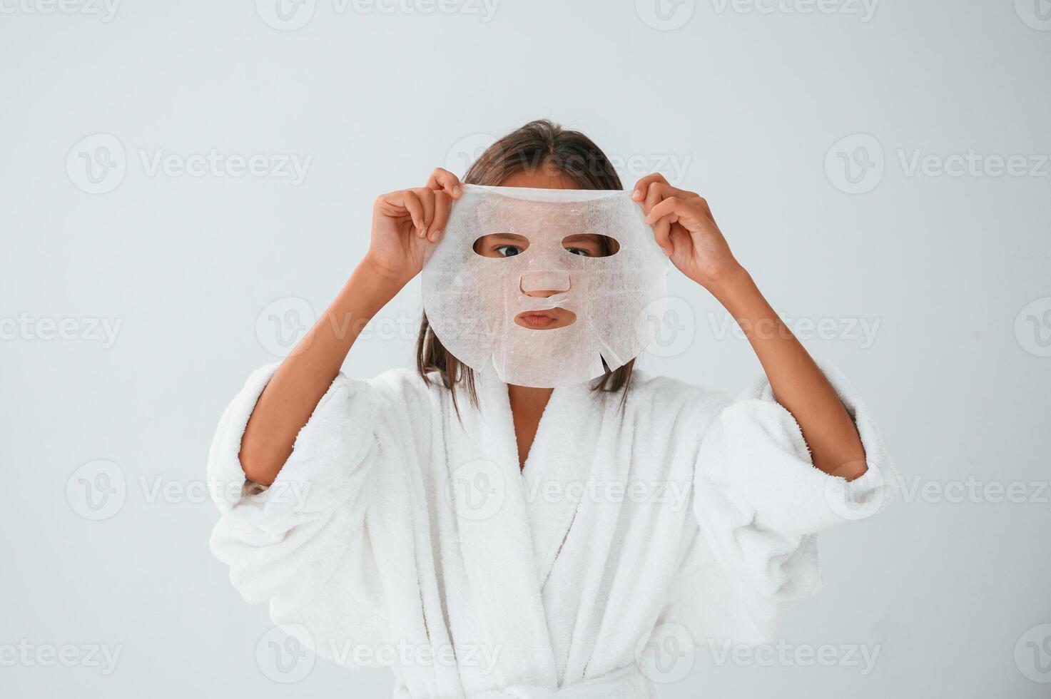 Playing and holding ,mask for the face. Conception of beauty and self care. Young girl is in the studio photo