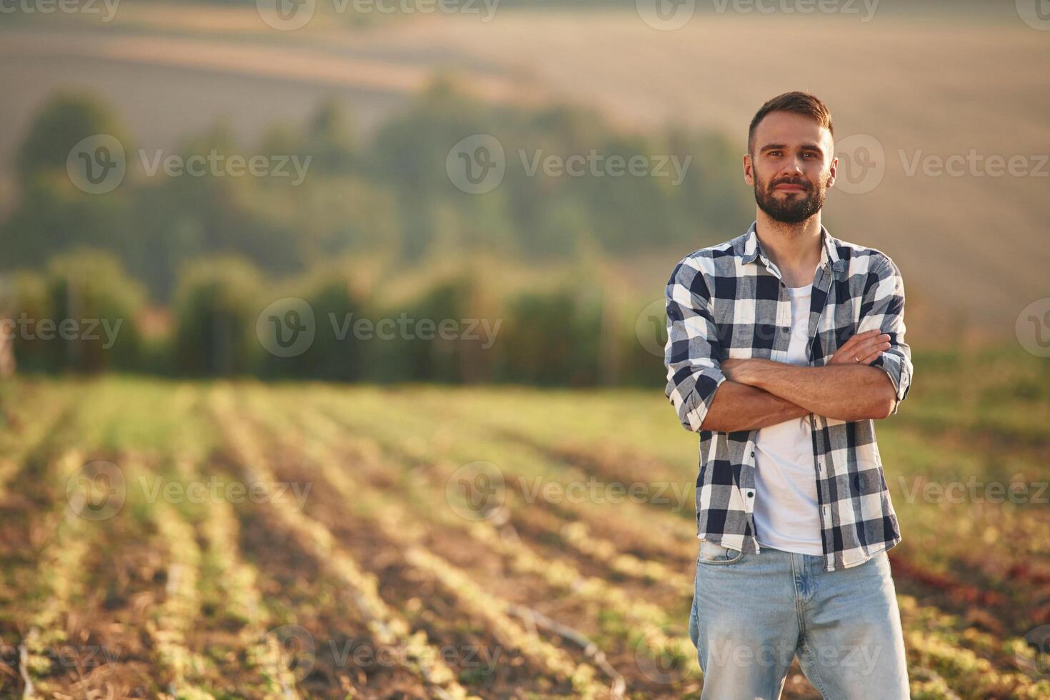 With arms crossed. Man is on the agricultural field, conception of work and harvest photo