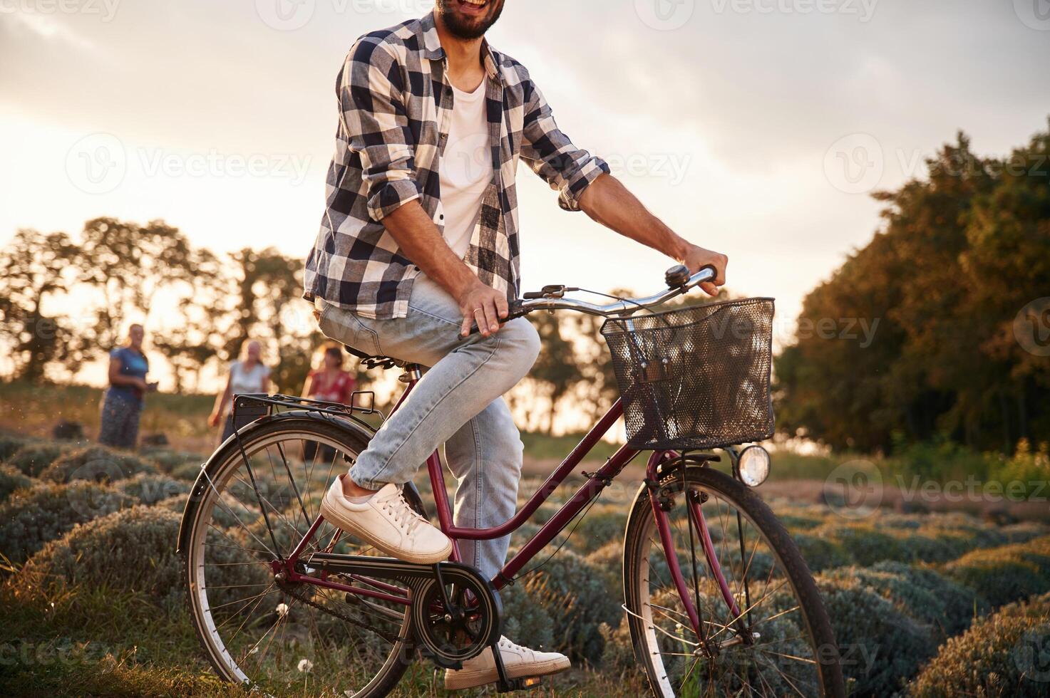 Handsome man in casual clothes is with bicycle on the agricultural field near greenhouse photo