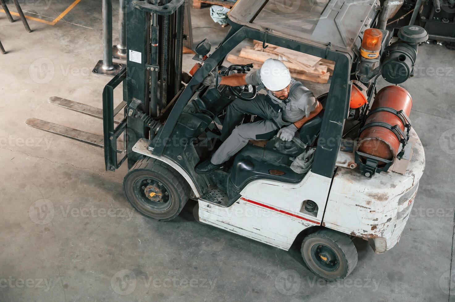 View from ,the, top, in the forklift. Young factory worker in grey uniform photo