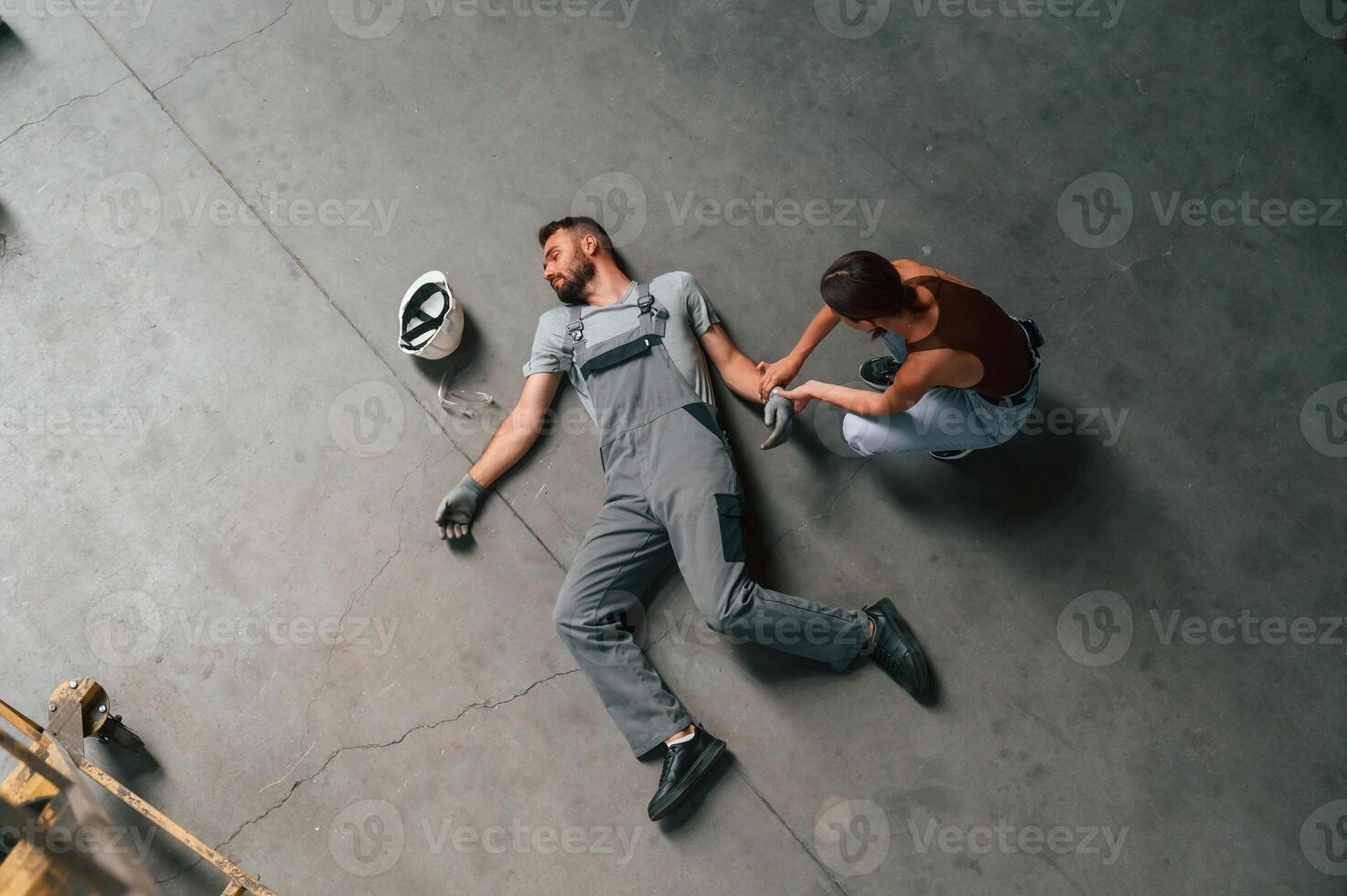 Woman hands checking pulse... Accident, male factory worker fell, without consciousness, lying down on the floor photo