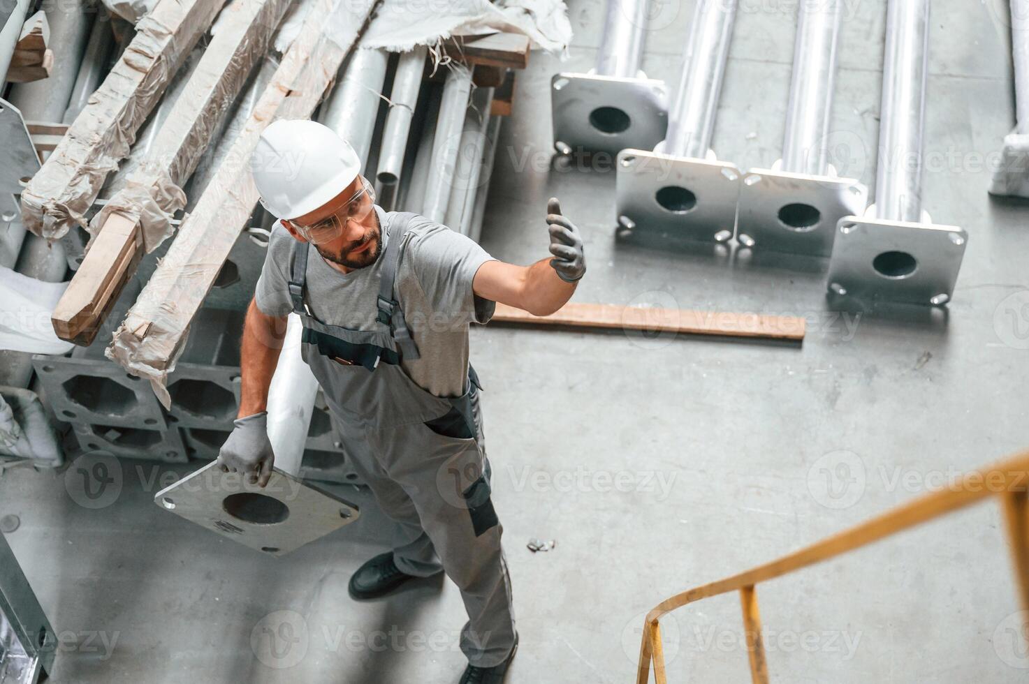 Making ,,gesture by hands. Young factory worker in grey uniform photo