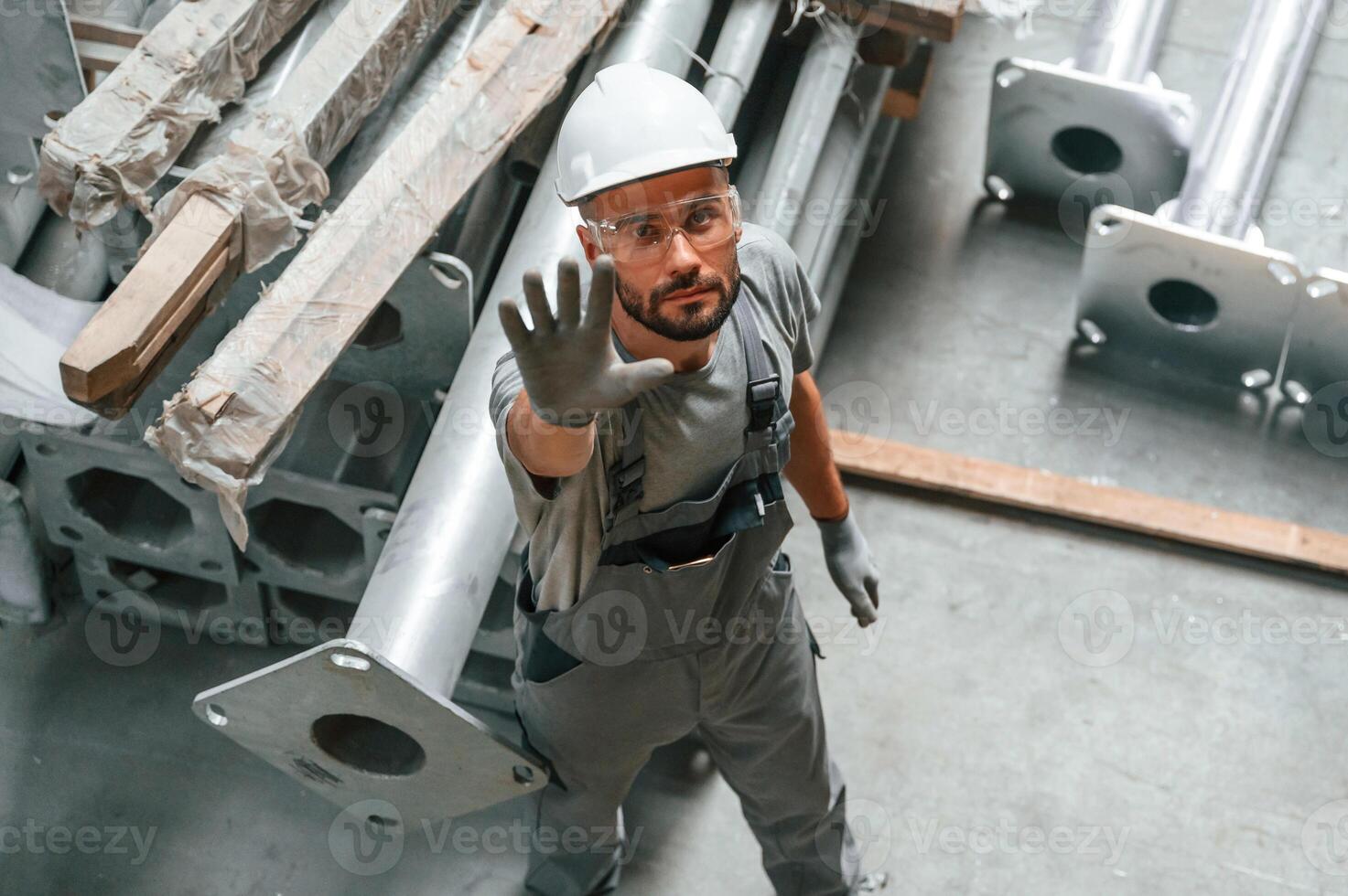 Top view... Making gesture by hands.,. Young factory worker in grey uniform photo