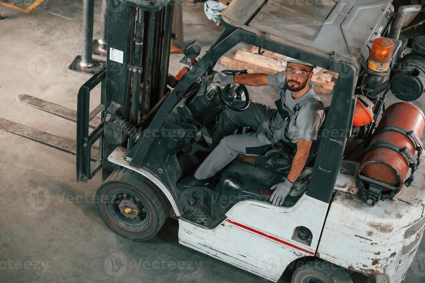 View ,from the top, in the forklift. Young factory worker in grey uniform photo