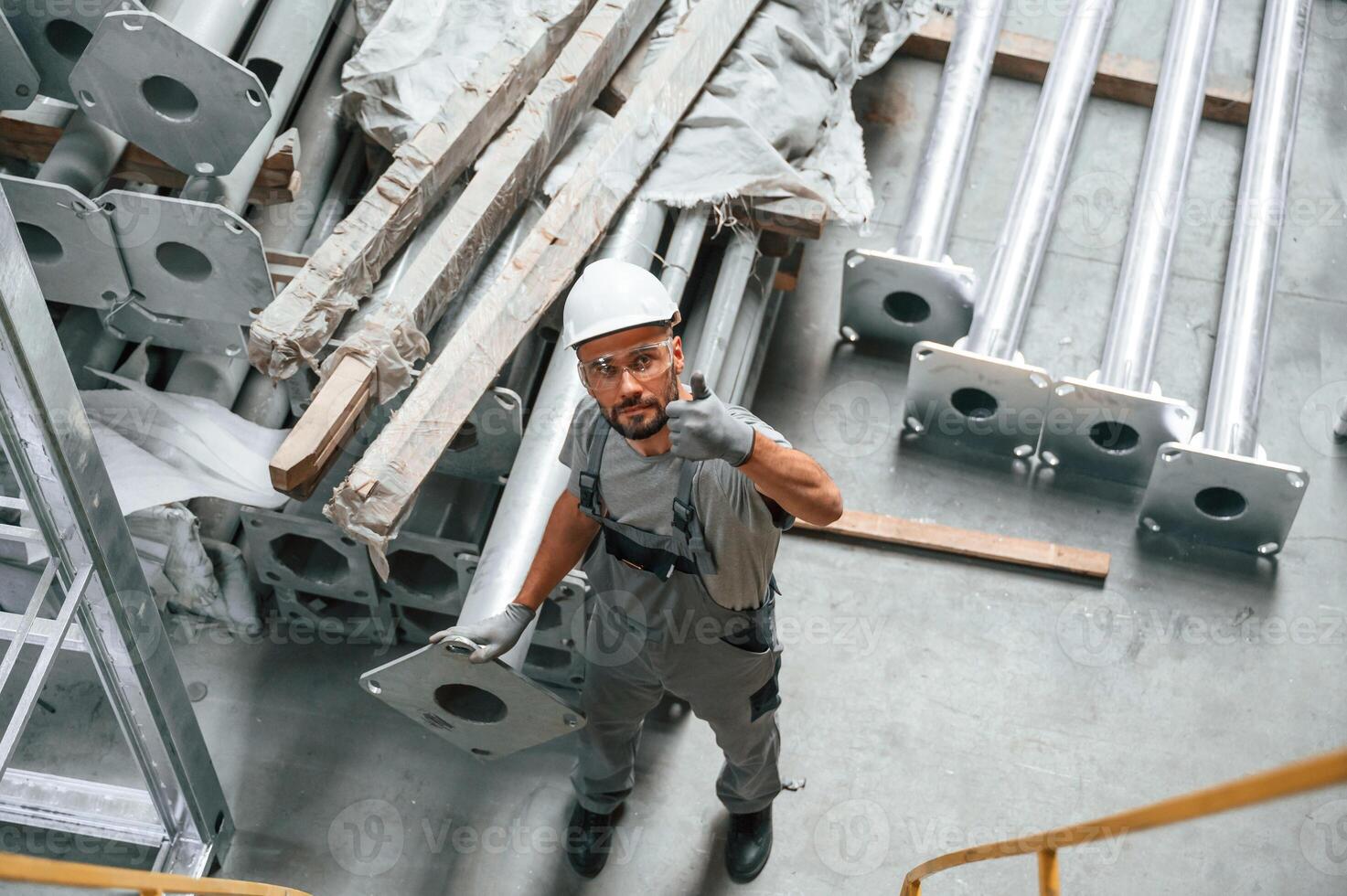 Top ,view... Making gesture by hands. Young factory worker in grey uniform photo